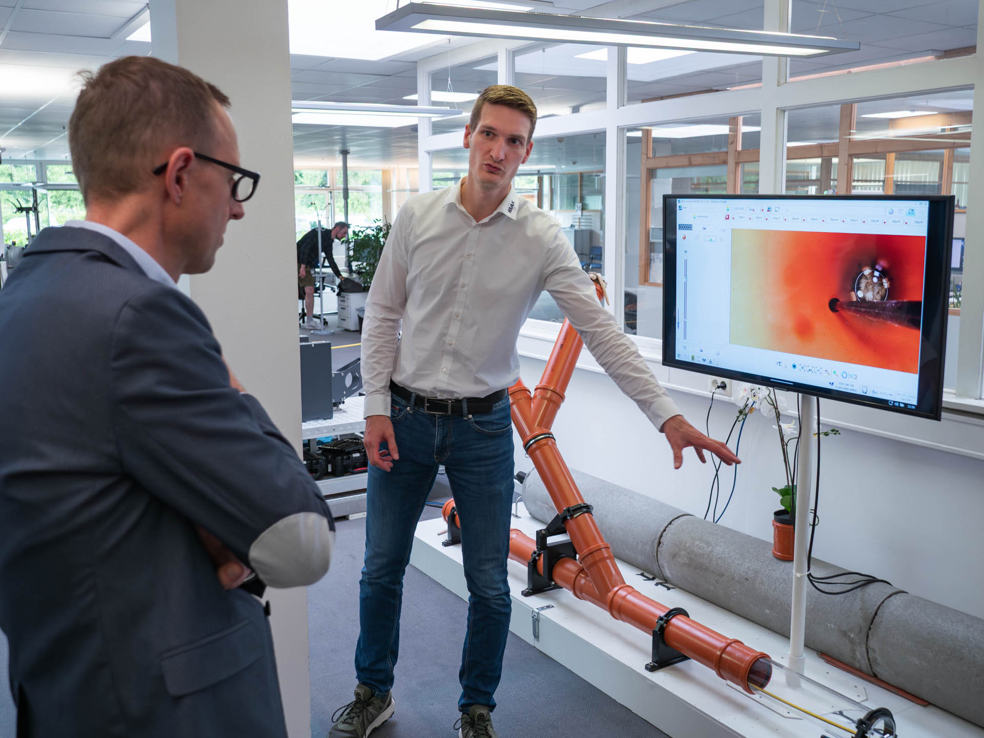 Dorian Hunger, Geschäftsführer von IBAK Helmut Hunger GmbH & Co. KG, präsentiert Dirk Schrödter, Chef der Staatskanzlei und Digitalisierungsminister, die prototypische KI-Steuerung für einen der Kanalroboter.